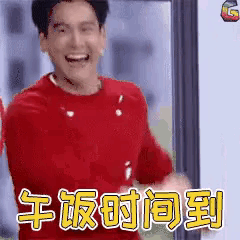 a man in a red shirt is smiling with chinese writing behind him .