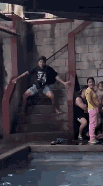 a group of people are walking down stairs towards a pool .