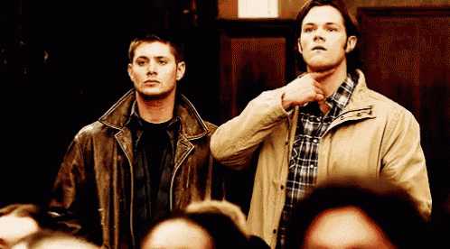 two men in leather jackets are standing next to each other in a crowded room .