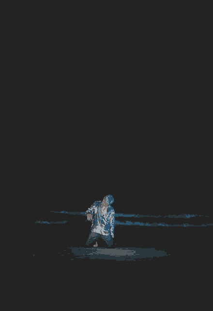 a man in a sequined shirt is standing in a dark room