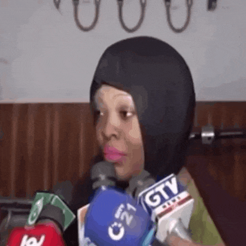 a woman wearing a hijab is sitting in front of a microphone .