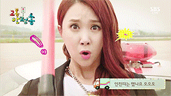 a woman with red hair is standing in front of a car with a sign that says sbs