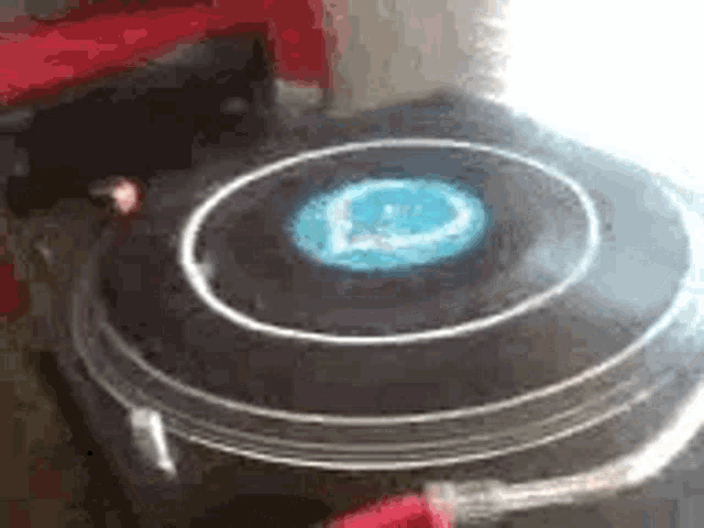 a record player is spinning a record on a turntable with a blue light coming out of it .