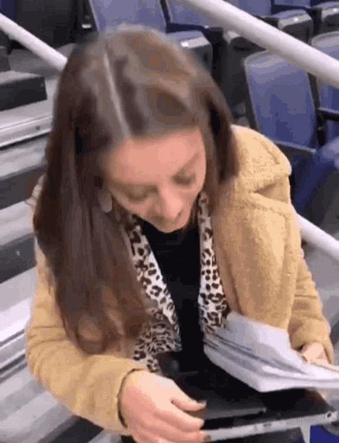 a woman in a leopard print jacket is sitting on stairs reading a book