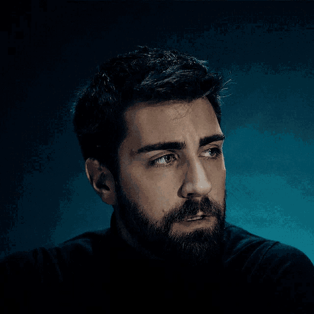 a man with a beard is wearing a black shirt and looking at the camera