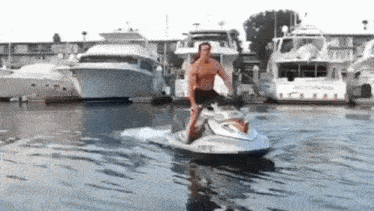 a man is riding a jet ski in the water with boats in the background .