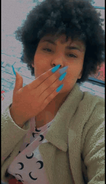 a woman covering her mouth with her hand while wearing blue nails