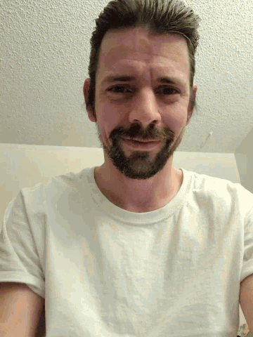 a man with a beard is wearing a white shirt and smiling