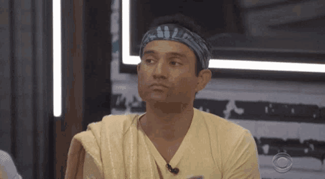 a man wearing a headband and a yellow shirt is looking at something
