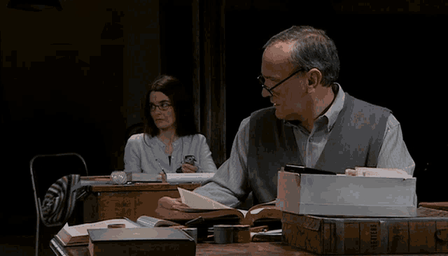 a man sits at a desk with a stack of books including one that says letters
