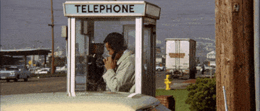 a man in a telephone booth talking on the phone