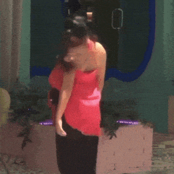 a woman in a pink dress is standing in front of a pink brick wall .