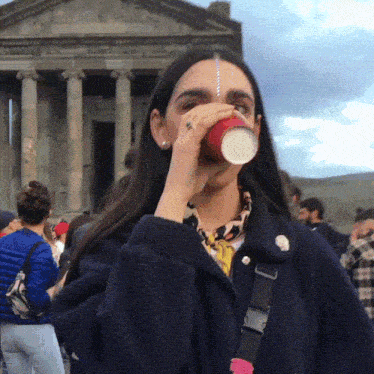 a woman drinking from a red cup with a ring on her finger