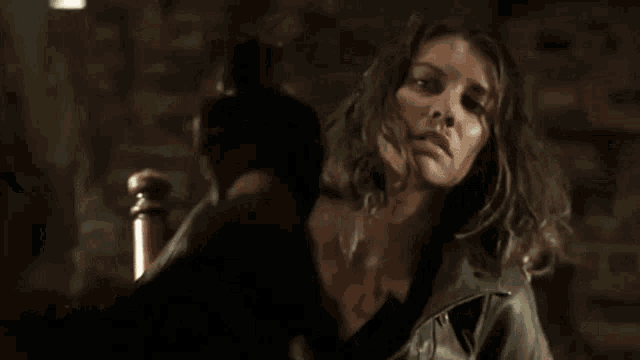 a woman with blood on her face is sitting in a chair looking at the camera .