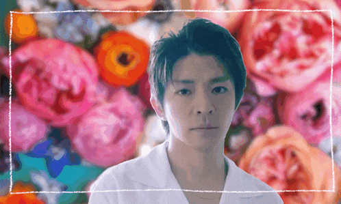 a man in a white shirt stands in front of a bunch of flowers