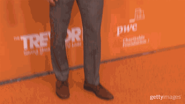 a man in a suit stands in front of a sign that says " revor "