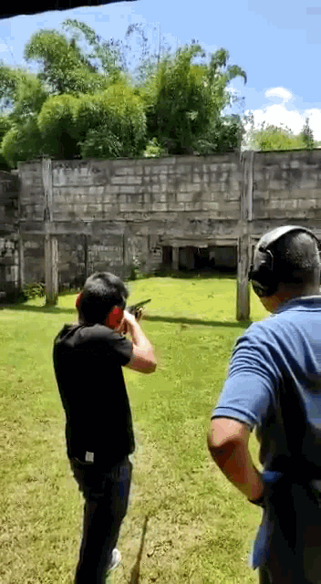a man is shooting a gun at another man in a shooting range .