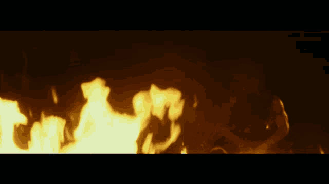 a person is laying on the ground in front of a large fire
