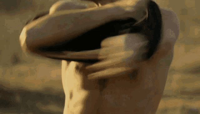 a man without a shirt is holding a black object in his hands