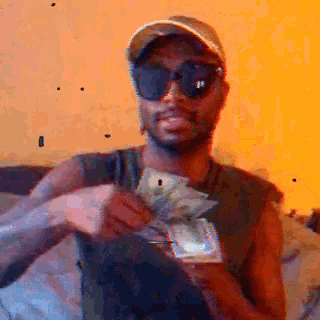 a man wearing sunglasses and a hat is holding a stack of money