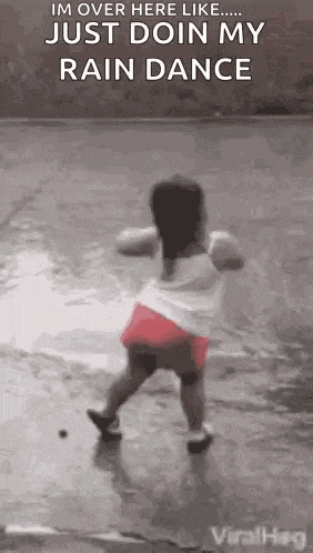 a little girl is dancing in the rain on the ground .