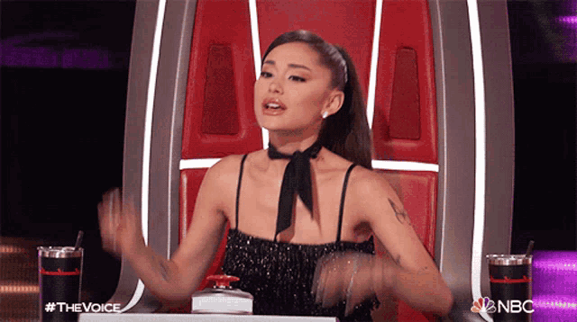 a woman in a black dress is sitting in a chair with nbc written on it