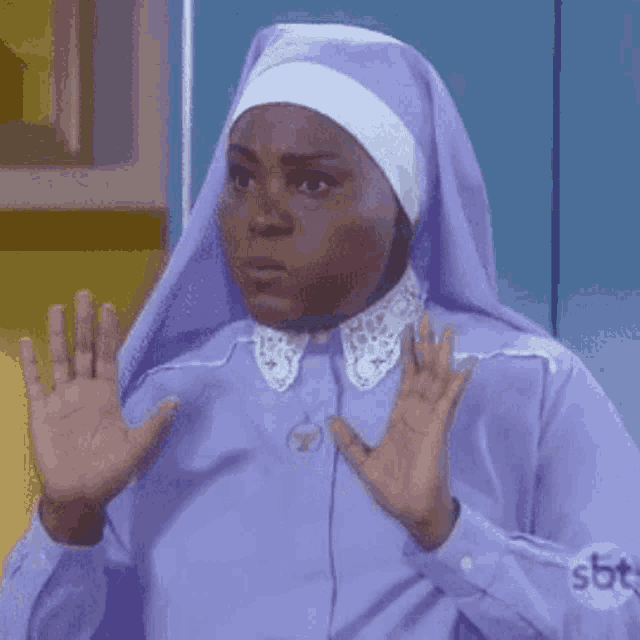 a woman in a purple nun costume is making a funny face with her hands .