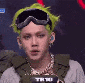 a young man with green hair and goggles is wearing a backpack .