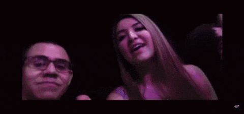 a boy and a girl are taking a selfie together in a dark room .
