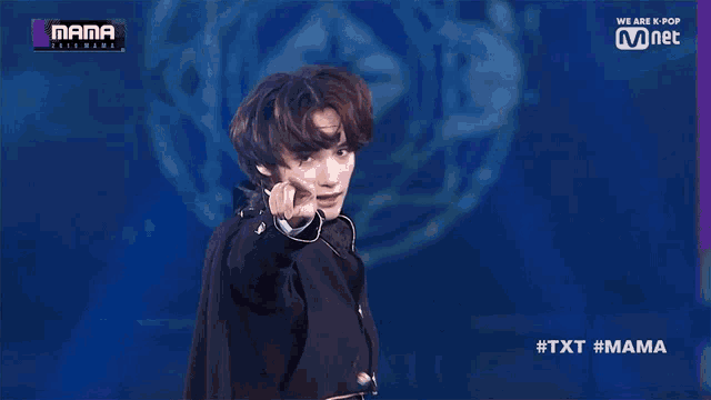 a man wearing a microphone stands on a stage in front of a sign that says we are k-pop