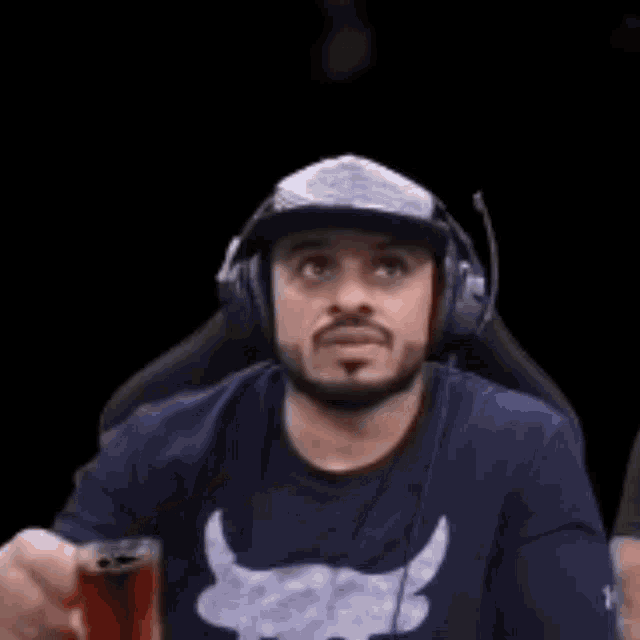 a man wearing headphones and a baseball cap is holding a cup of coffee .