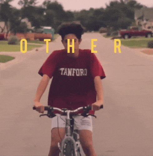 a man wearing a tanford shirt is riding a bike on a street