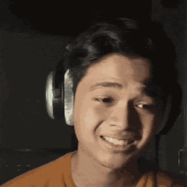 a young man wearing headphones is smiling in the dark .