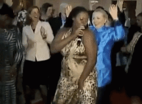a woman in a leopard print dress is singing into a microphone while dancing with other people .