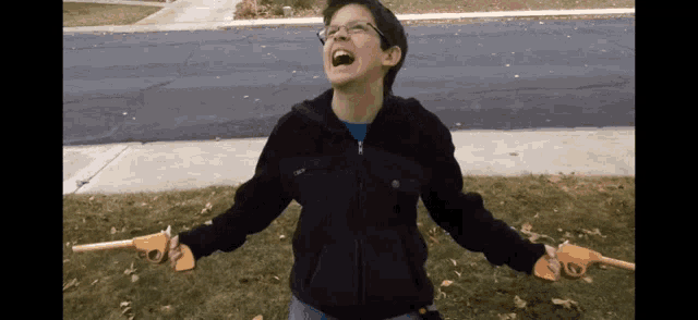 a boy in a black jacket is holding two guns in his hands