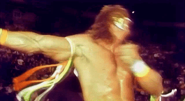a wrestler without a shirt is dancing in front of a crowd with a sign that says pa on it