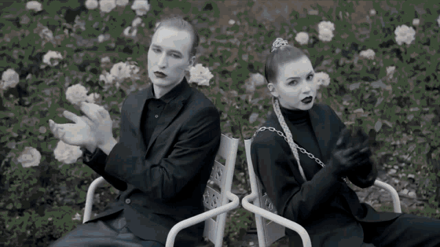 a man and a woman are sitting back to back in front of roses