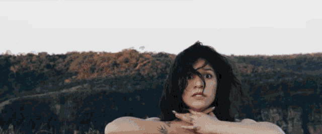a woman with a tattoo on her arm is standing in front of a mountain