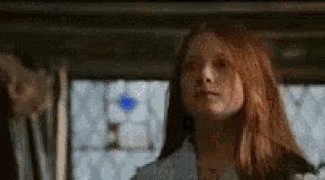 a woman with red hair is sitting in a car looking at the camera .