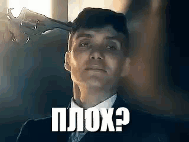 a man in a suit is holding a gun in his head .