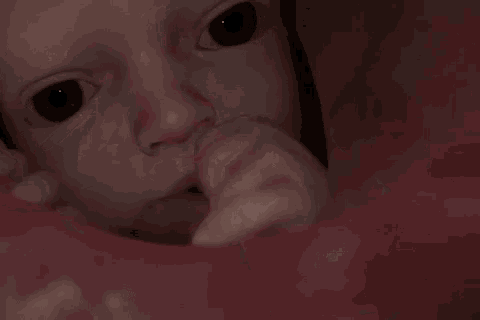 a close up of a baby 's face with a person 's finger in it