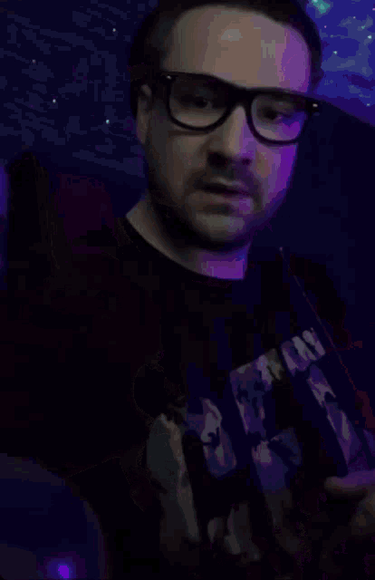 a man wearing glasses holds a bottle in his hand