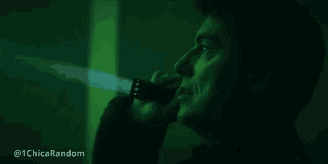 a man is holding a flashlight in his hand in a green room .