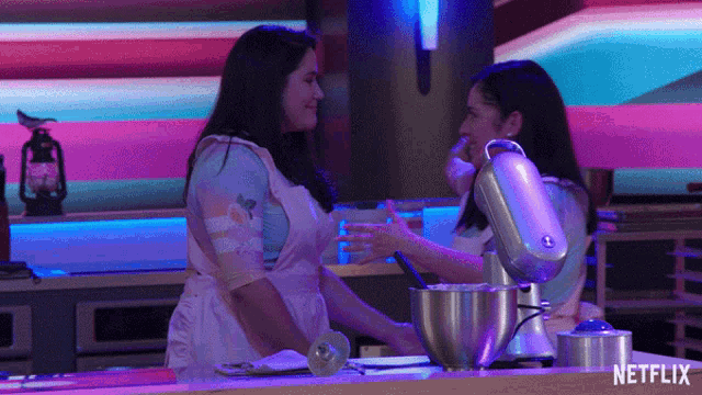 two women are hugging in a kitchen with a netflix logo in the background