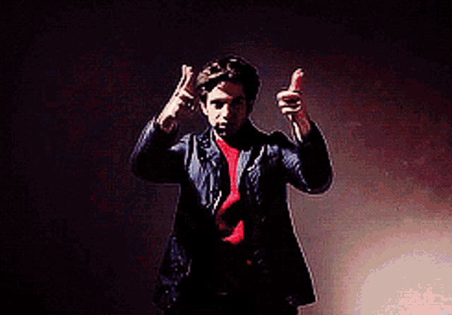 a man in a red shirt and a blue jacket is giving a thumbs up