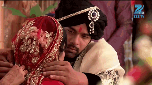 a man in a turban is putting a ring on a woman 's finger in front of a sign that says zee tv