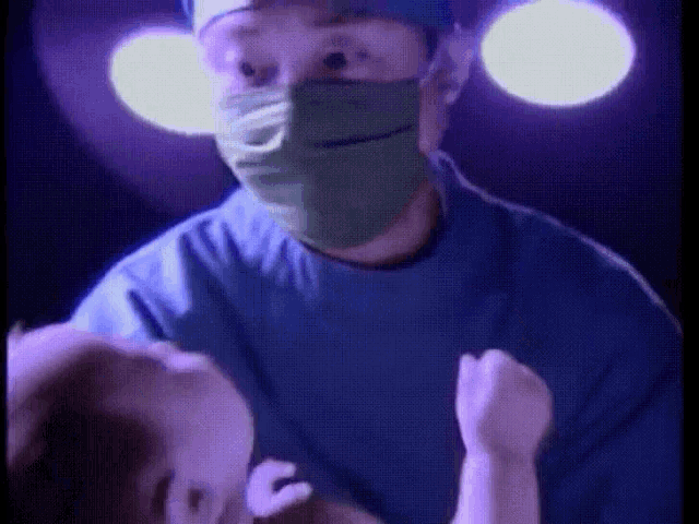 a surgeon wearing a mask and gown is holding a baby