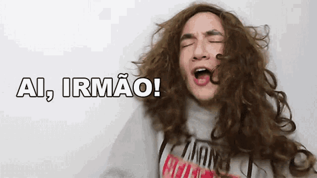 a man with long curly hair is screaming with the words ai irmao above him