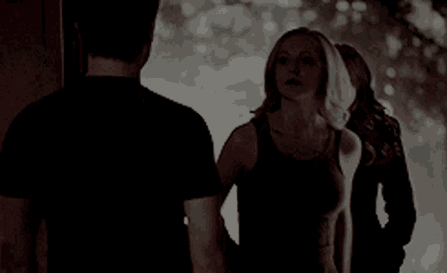 a woman in a black tank top stands in front of a man