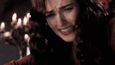 a close up of a woman crying in front of a chandelier .